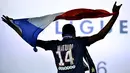 Pemain Paris Saint-Germain, Blaise Matuidi mengibarkan bendera Prancis saat  naik podium dalam perayaan juara liga prancis di Stadion Parc des Princes stadium, Paris,(14/5/2016).  (AFP/Franck Fife)