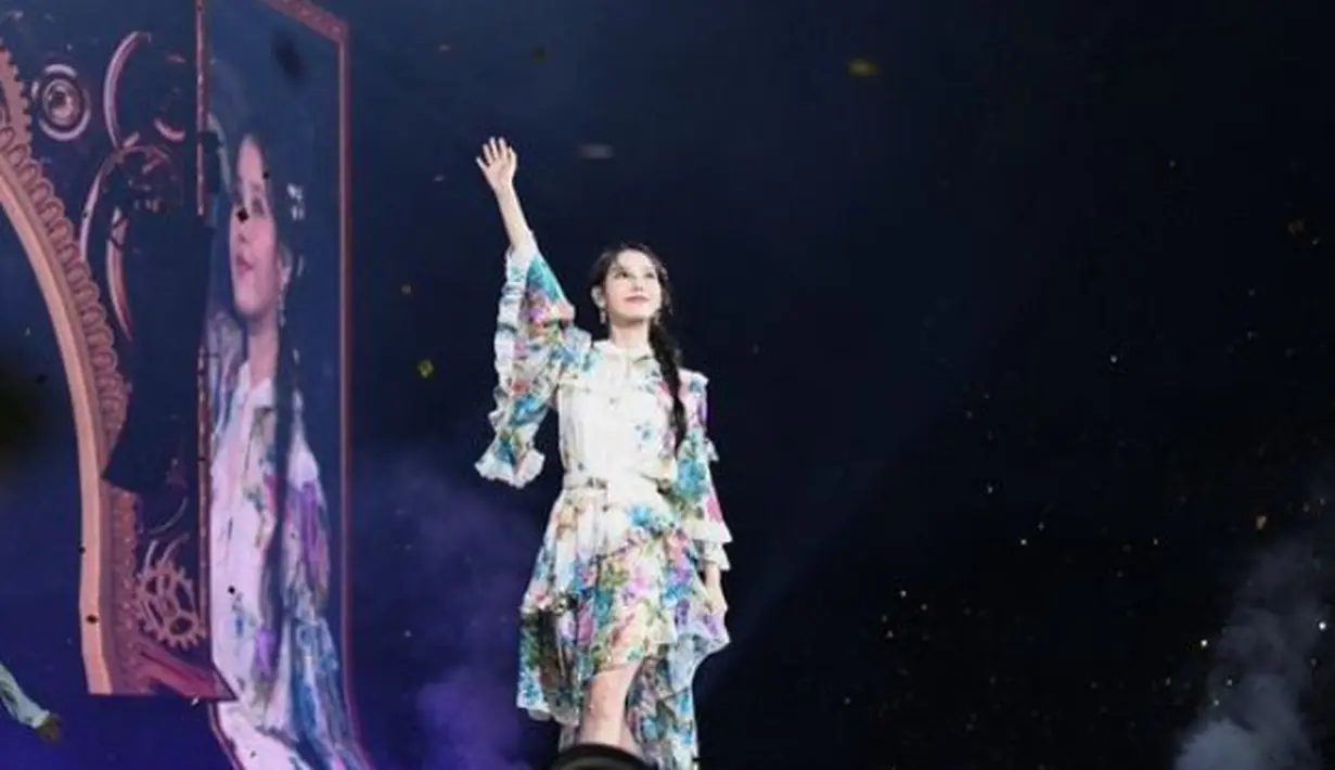 IU tampil dengan dress ruffle motif bunga-bunga yang membuatnya elegan. Dengan gaya rambut kuncir belakang model kepang. [@dlwlrma]