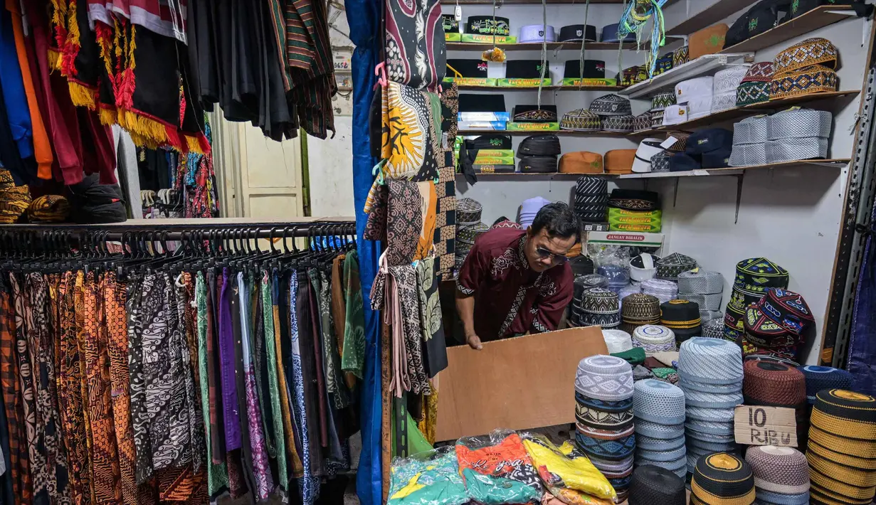 Seorang pedagang menata peci untuk dijual selama bulan suci Ramadan di dekat Masjid Sunan Ampel, Surabaya, Jawa Timur, pada Minggu 8 Maret 2026. Sepanjang Ramadan, kawasan sekitar Masjid Sunan Ampel, Surabaya, Jawa Timur, berubah menjadi pusat belanja dan kuliner yang kental dengan nuansa Timur Tengah. (JUNI KRISWANTO/AFP)