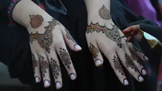 Seorang ahli kecantikan mengecat tangan pelanggan dengan henna tradisional untuk persiapan perayaan Lebaran Idul Fitri mendatang, di Karachi, Pakistan, Kamis, 20 April 2023. (AP Photo/Fareed Khan)
