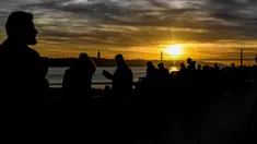 Orang-orang menikmati matahari terbenam di Ribeira das Naus di Lisbon (17/12). Lisboa atau Lisbon merupakan ibu kota  Portugal. (AFP Photo/Patricia De Melo Moreira)