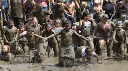 Ratusan anak berlari ke dalam kubangan berisi lumpur saat perayaan Mud Day atau Hari Lumpur Tahunan di Westland, Michigan, AS, Selasa (10/7). Dalam Mud Day kali ini para pesertanya yang ikut adalah anak-anak.  (AP/Carlos Osorio)