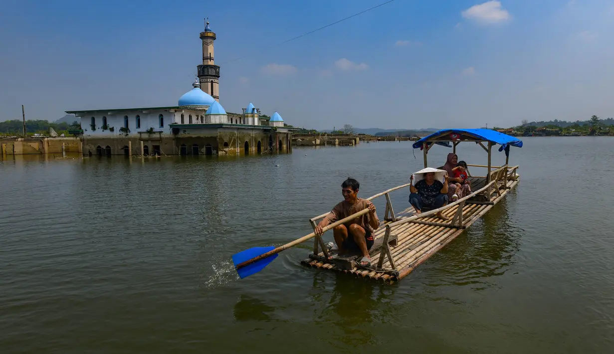 Warga menggunakan perahu  menyaksikan puing-puing bangunan mesjid dan rumah yang kembali muncul di kawasan Bendungan Karian yang mengering di Kampung Somang, Lebak, Banten, Jumat, 7 Agustus 2026. (KLY/ Arie Basuki)