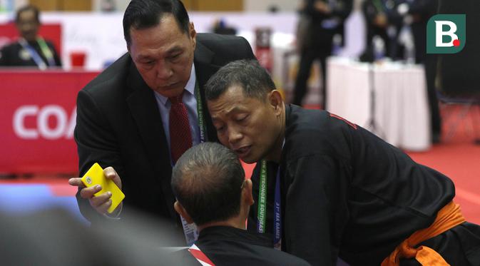 Sempat ada insiden antara Ketua Harian PB Ikatan Pencak Silat Indonesia (IPSI), Benny Sumarsono (kiri) dengan pelatih pencak silat Indonesia,  Bondan. Benny lalu meminta Bondan untuk keluar. Dia menunjuk-nunjuk pintu keluar venue silat SEA Games 2021, untuk meminta Bondan segera angkat kaki dari lapangan. (Bola.com/Ikhwan Yanuar)