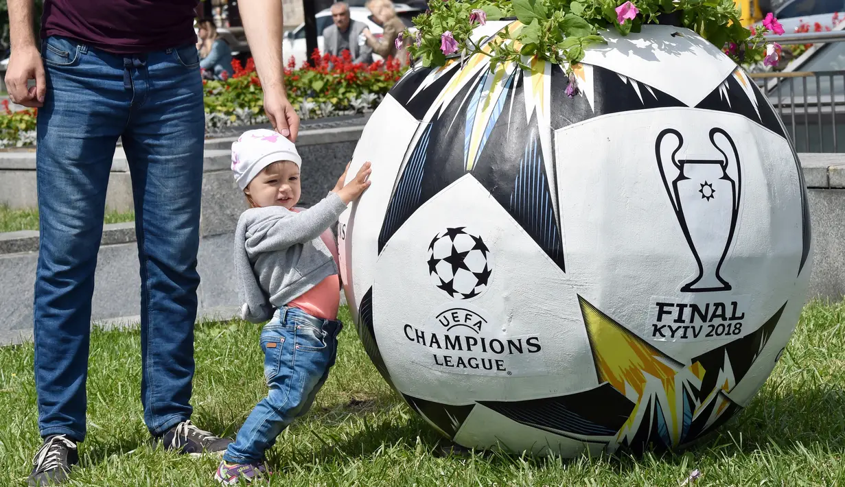 Seorang anak berdiri di sebelah pot bunga berbentuk seperti bola di Independence Square, Kiev, Ukraina (22/5). Final Liga Champions antara Real Madrid dan Liverpool akan berlangsung pada 26 Mei mendatang di Olimpiyskiy Stadion. (AFP Photo/Sergei Supinsky)