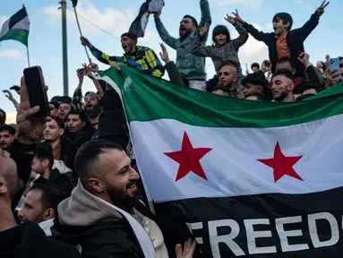 Seorang demonstran memegang bendera oposisi Suriah saat anggota komunitas Suriah meneriakkan slogan-slogan di alun-alun Syntagma, Athena untuk merayakan berakhirnya rezim Bashar al-Assad pada tanggal 8 Desember 2024. (Angelos TZORTZINIS/AFP)