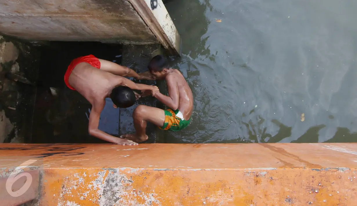 Dua orang anak bercanda ketika bermain dan berenang di anak Kali Ciliwung, Jakarta, Rabu (13/7). Bersihnya kali yang berada di Ibu Kota itu dimanfaatkan anak-anak sekitar untuk berenang sambil mengisi waktu libur sekolah. (Liputan6.com/Immanuel Antonius) 