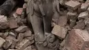 Patung berdiri di antara puing-puing kuil bersejarah yang hancur akibat gempa berkekuatan 7,8  di sekitar Kathmandu, Nepal  (30/4/2015). Lebih dari 5.000 orang tewas akibat gempa yang meluluhlantakkan Nepal pada 25 April 2015 lalu. (Nicolas Asfouri/AFP)