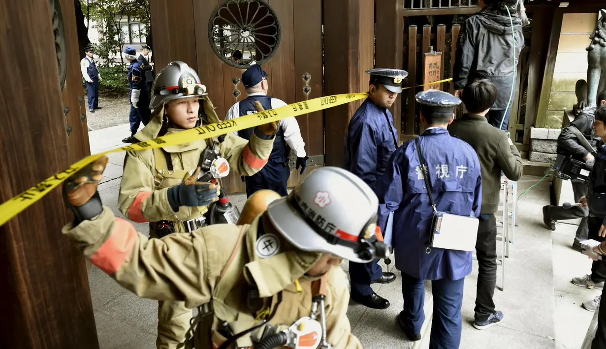 Petugas Polisi dan pemadam kebakaran saat melakukan investigasi di gerbang selatan Yasukuni Shrine dimana ledakan terjadi, Tokyo, Jepang, (23/11). Kuil ini merupakan simbol militerisme Jepang di masa lalu (REUTERS/Kyodo)