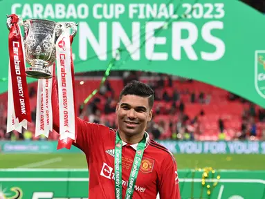 Pemain Manchester United, Casemiro mengangkat trofi Carabao Cup 2022/2023 setelah mengalahkan Newcastle dengan skor 2-0 pada laga final yang berlangsung di Stadion Wembley, London, 26 Februari 2023. Casemiro didatangkan ke Old Trafford dengan biaya 70.65 juta euro dari Real Madrid pada bursa transfer musim panas 2022/2023. Kedatangannya benar-benar mengubah peruntungan MU. Casemiro berhasil membuat klub berjuluk Setan Merah tersebut kembali keompetitif lagi. (AFP/Glyn Kirk)