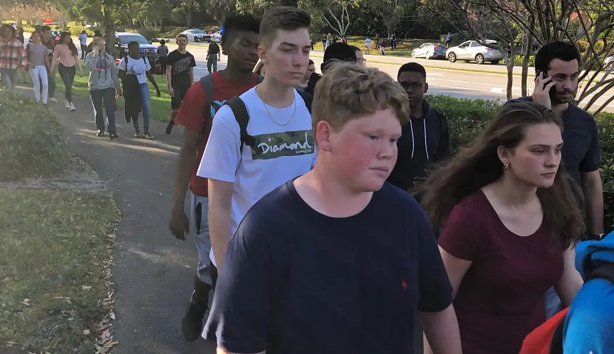 Sejumlah siswa dievakuasi ketika terjadi penembakan massal sekolah menengah Marjory Stoneman Douglas di Parkland, Florida, Rabu (14/2). Serangan ini akan menjadi salah satu tragedi penembakan paling mematikan dalam sejarah AS. (Michele Eve Sandberg/AFP)