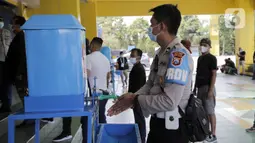 Seorang petugas kepolisian mencuci tangan sebelum melakukan swab antigen jelang pertandingan sepak bola Piala Menpora 2021 di Stadion Kanjuruhan, Malang, Jawa Timur, Senin (22/3/2021). (Bola.com/Arief Bagus)