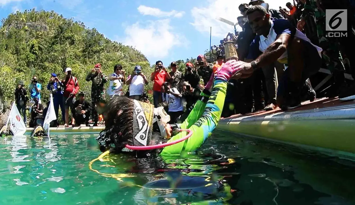 Ketua Umum WASI, Tri Suswati Karnavian membawa api obor Asian Games 2018 di perairan Pulau Piaynemo, Raja Ampat, Papua Barat, Kamis (26/7). Kegiatan ini sebagai bentuk dukungan perempuan terhadap kesuksesan Asian Games 2018. (Liputan6.com/HO/Mabes Polri)