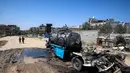 Seorang anak laki-laki mengambil air ke dalam jeriken dari kendaraan mobile tangki air yang hancur akibat pengeboman Israel di kamp Nuseirat untuk pengungsi Palestina di Jalur Gaza tengah pada 14 Juli 2025. (Eyad BABA/AFP)