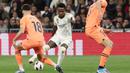 Pemain Real Madrid, Vinicius Junior berusaha melewati pemain Valencia pada laga Liga Spanyol di Stadion Santiago Bernabeu, Sabtu (11/11/2023). Berkat kemenangan ini, Real Madrid tetap berada di peringkat dua klasemen sementara La Liga, sementara Valencia tertahan di peringkat 10. (AFP/Thomas Coex)