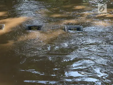 Sejumlah makam terendam banjir di kampung Arus Cawang, Jakarta Timur, Jumat (26/4). Ketinggan banjir kurang lebih satu meter terjadi akibat luapan kali Ciliwung dan intensitas curah hujan di kawasan Bogor Jawa Barat sangat tinggi sehingga aktivitas warga terhambat. (merdeka.com/Imam Buhori)