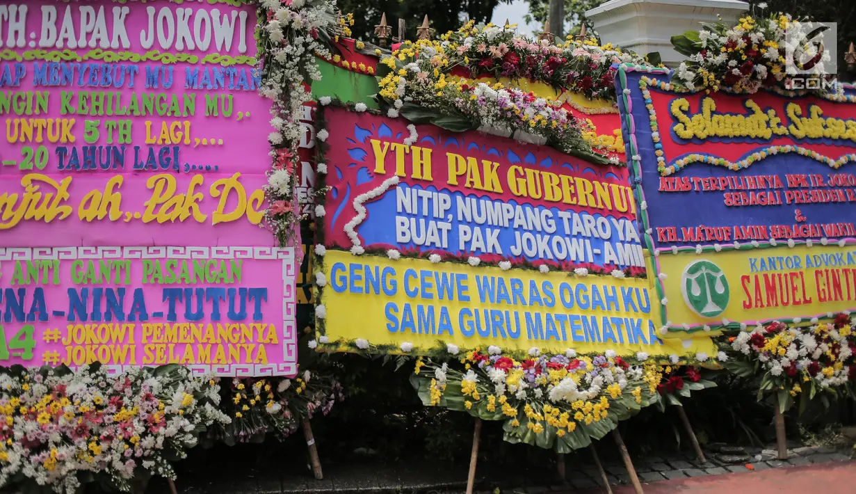 Sejumlah karangan bunga bertuliskan ucapan selamat untuk Joko Widodo (Jokowi) dan Ma'ruf Amin di depan pagar gedung Sekretariat Negara, Jakarta, Senin (22/4). Karangan bunga dari pendukung Jokowi-Ma'ruf tersebut ditujukan atas kemenangan pasangan itu pada Pilpres 2019. (Liputan6.com/Faizal Fanani)