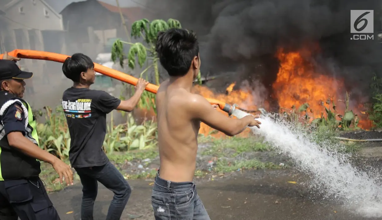 Warga membantu petugas pemadam kebakaran memadamkan api yang melalap gudang di Jalan Kampung Bandan, Ancol, Jakarta Utara, Kamis (5/7). (Liputan6.com/Faizal Fanani)