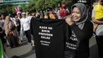 Pedagang memperlihatkan kaus #2019GantiPresiden yang dijajakan saat Car Free Day di kawasan Bundaran HI, Jakarta, Minggu (29/4). Memanasnya suasana politik nasional dimanfaatkan pedagang berjualan atribut #2019GantiPresiden. (Liputan6.com/Faizal Fanani)