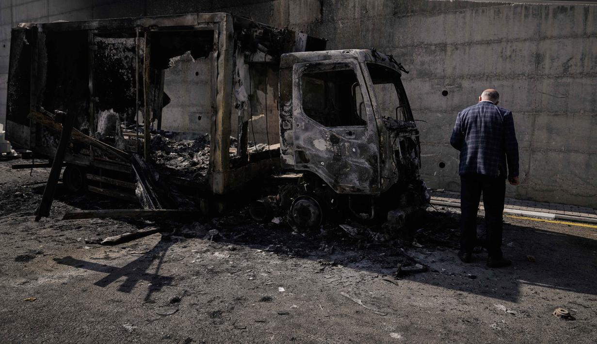 Penyerangan tersebut mengakibatkan cedera, penangkapan, serta kerusakan material yang luas. Tampak dalam foto, warga Palestina memeriksa kendaraan yang terbakar setelah serangan yang dilakukan oleh pemukim Israel pada hari sebelumnya di kawasan industri di desa Beit Lid, Tepi Barat, dekat Tulkarm, Rabu 12 November 2025. (AP Photo/Majdi Mohammed)