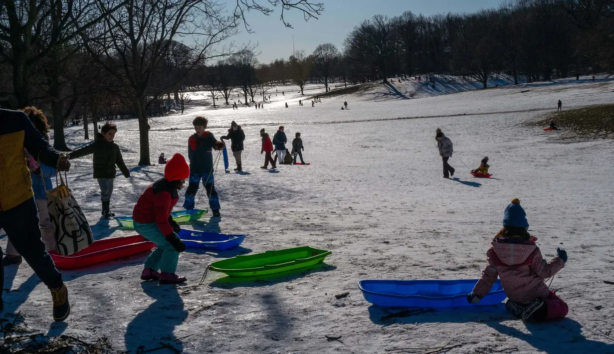 Anak-anak bermain kereta luncur di Taman Prospect Brooklyn pada sore hari di musim dingin tanggal 21 Januari 2024 di New York City. (SPENCER PLATT/GETTY IMAGES NORTH AMERICA/Getty Images via AFP)