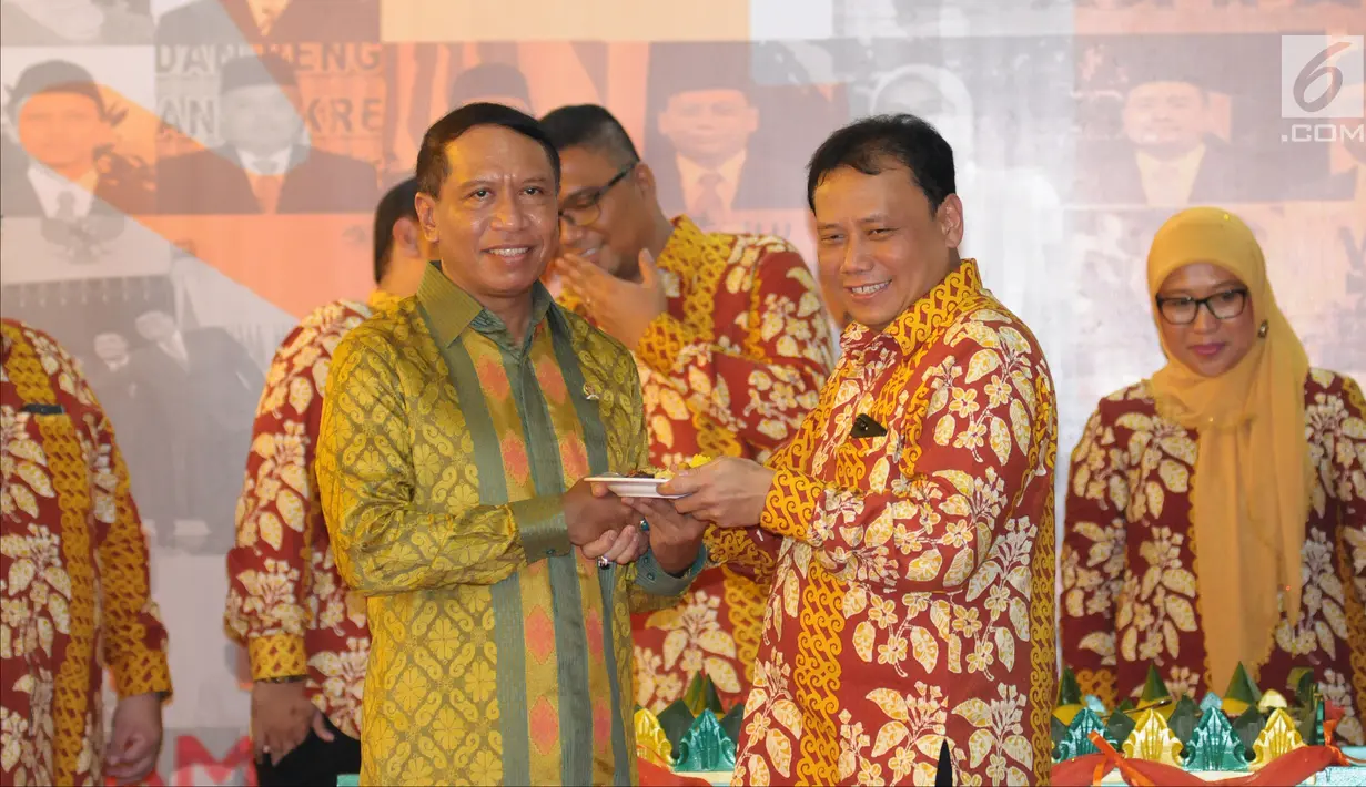 Ketua Bawaslu, Abhan menyerahkan potongan tumpeng kepada Ketua Komisi II DPR RI, Zainuddin Amali pada perayaan HUT 1 Dasawarsa Bawaslu di Jakarta, Senin (9/4). (Liputan6.com/Helmi Fithriansyah)