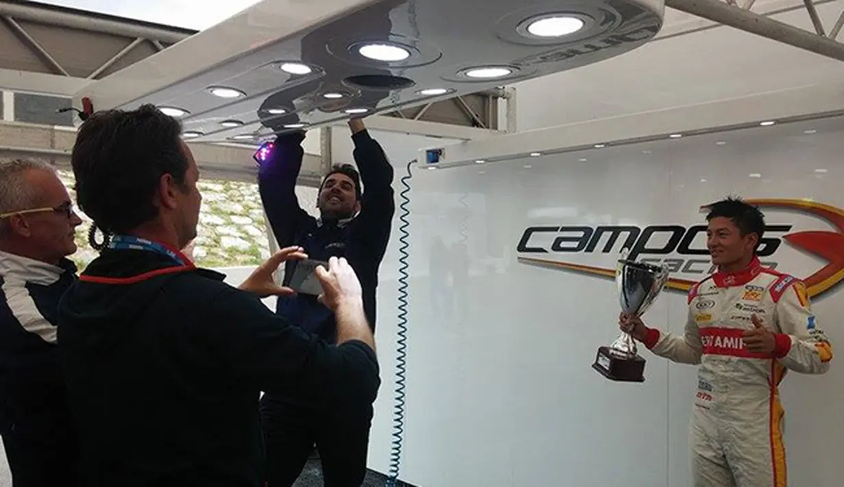Rio Haryanto merayakan trofi juara bersama para kru tim Campos Racing. (Bola.com/Reza Khomaini)