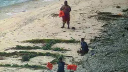 Tiga orang pelaut diselamatkan oleh pasukan AL Amerika Serikat dari pulau tak berpenghuni Faradik, Mikronesia, 7 April 2016. Mereka menuliskan kata "help" menggunakan dahan pohon palem di atas hamparan pasir pantai. (ENSIGN JOHN KNIGHT/NMCO/AFP)