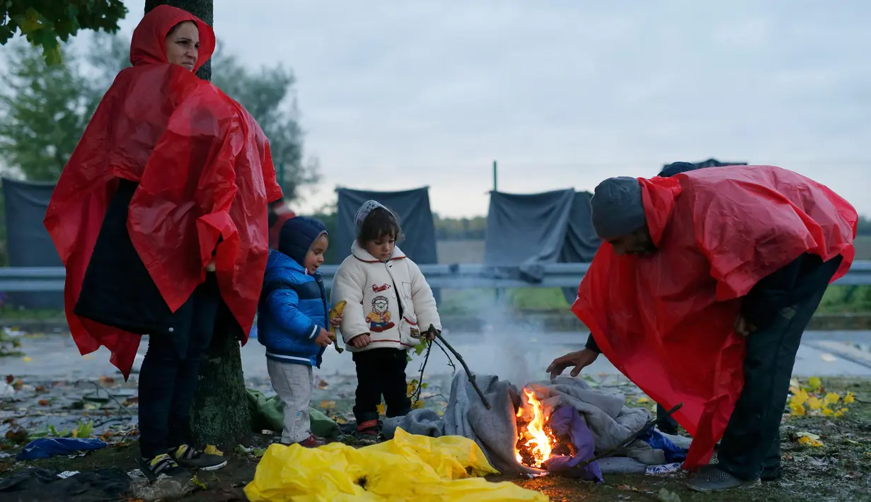 Pengungsi menghangatkan diri saat menunggu menyeberang perbatasan dari Slovenia menuju Trnovec, Kroasia, Senin (19/10). Ribuan orang terjebak cuaca dingin di desa perbatasan Serbia Berkasovo usai Kroasia membendung para pendatang. (REUTERS/Antonio Bronic)