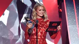 Paris Hilton saat mengumumkan pemenang selama iHeartRadio Music Awards 2018 di Inglewood, California, AS (11/3). Paris Hilton datang bersama tunangannya Chris Zylka. (AFP Photo/Christopher Polk)