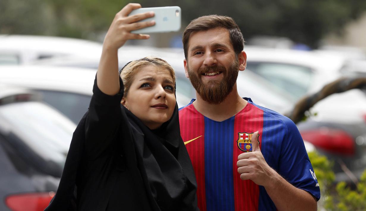 Reza Parastesh, seorang warga Iran yang memiliki wajah mirip Lionel Messi diajak selfie oleh warga di jalanan Tehran, Iran, Senin (8/5/2017). (AFP/Atta Kenare)