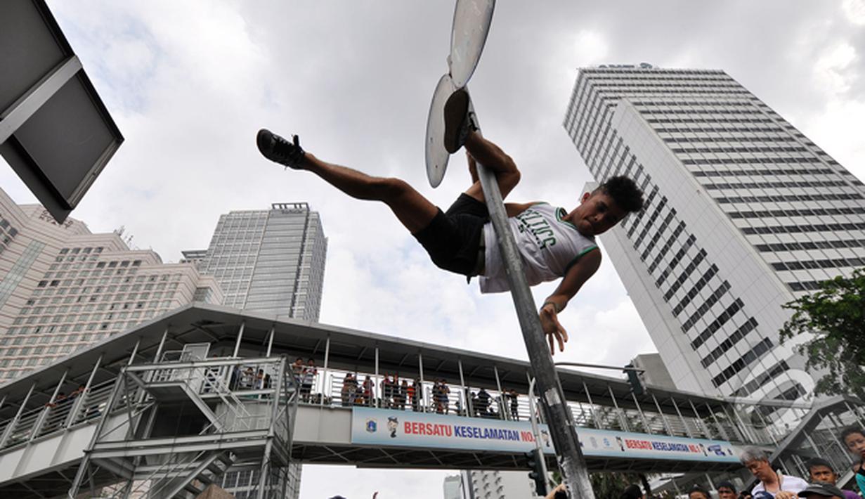 Tiang rambu lalu lintas menjadi arena aksi dari pegiat 'Pole Dance'  di Bundaran HI, Jakarta, Minggu (18/1/2015). (Liputan6.com/Miftahul Hayat)