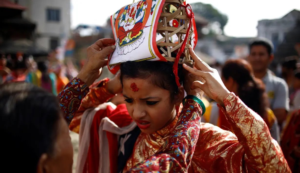 Seorang bocah dipakaikan mahkota saat perayaan Gaijatra Festival atau Festival Sapi di Kathmandu, Nepal, Jumat (19/8). Sapi dianggap sebagai binatang suci di Nepal yang membantu jiwa untuk mencapai surga. (REUTERS/ Navesh Chitrakar)