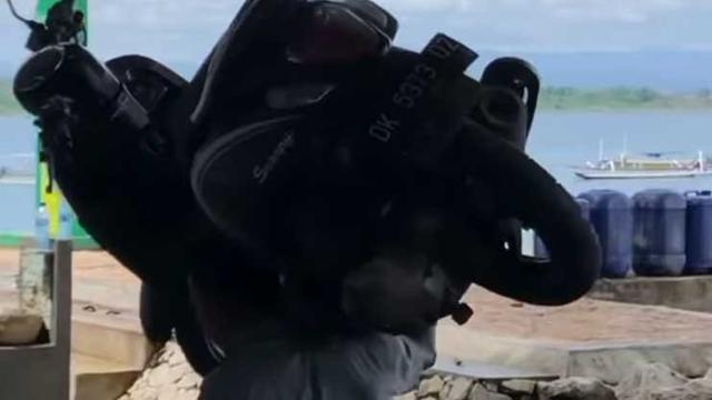 Orang ini menggendong motor di pinggir pantai di Bali (Dagelan)