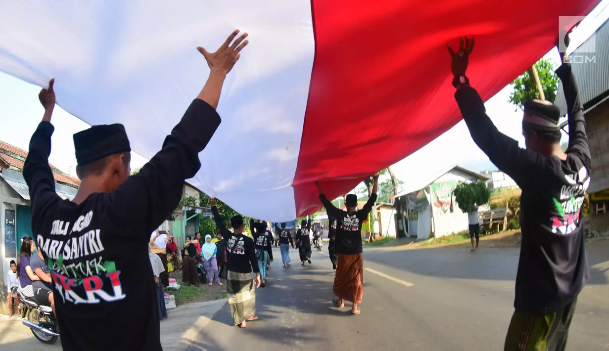 Sejumlah santri dari Pondok Pesantren Ashabul Kahfi membawa bendera Merah Putih besar saat mengikuti pawai Hari Santri Nasional 2017 di Gunungpati, Semarang (22/10). (Liputan6.com/Gholib)