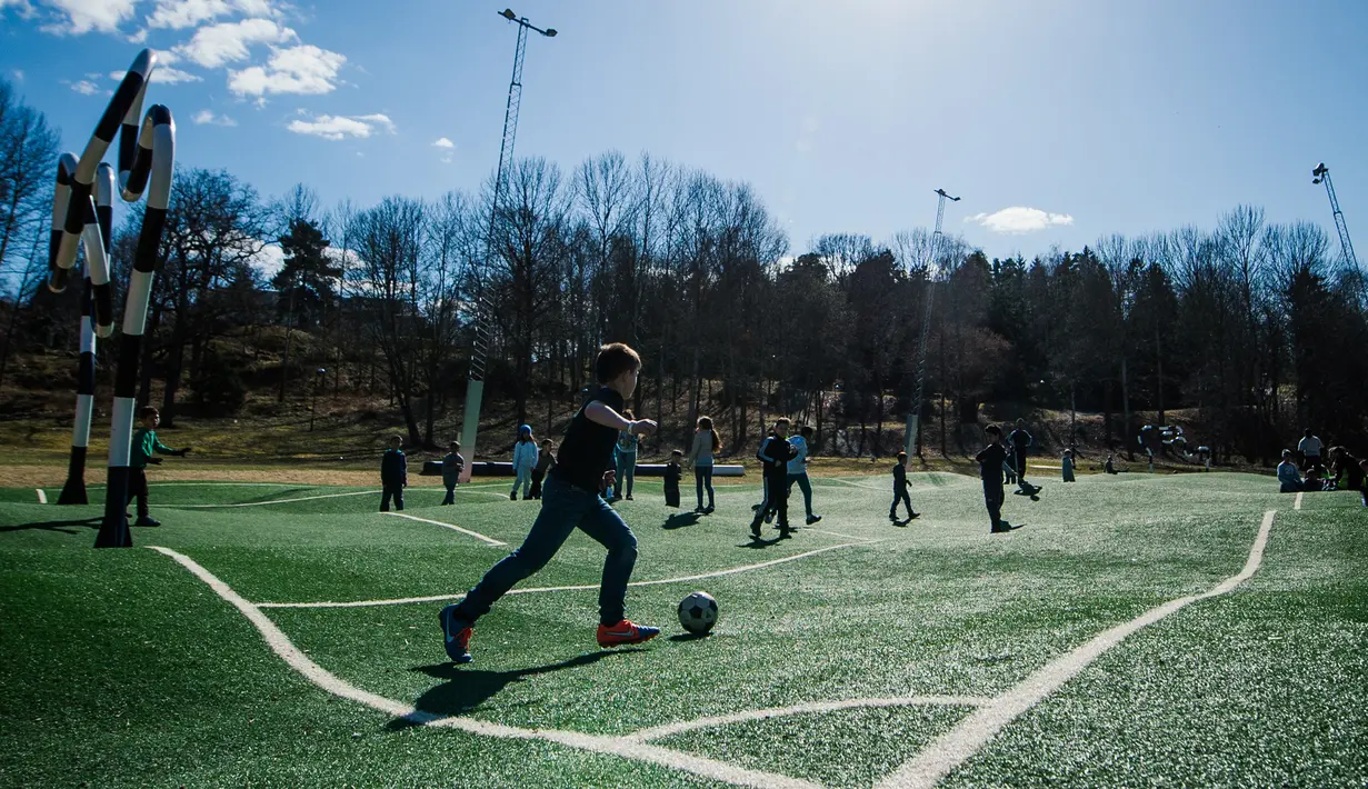 Keseruan anak-anak bermain di lapangan Puckelboll di Skarholmen, Stockholm, Swedia, 11 April 2016.  Lapangan Puckelboll adalah lapangan sepak bola buatan yang bergelombang dan merupakan karya seni dari Johan Storm. (Jonathan NACKSTRAND/AFP) 