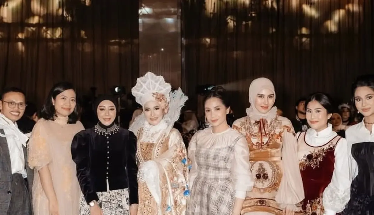 Nagita Slavina tampil mengenakan inner putih lengan panjang dengan kerah circle berkerut. Dipadukan long dress motif kotak-kotak model spaghetti strap. [@drfeninugraha.spgk]