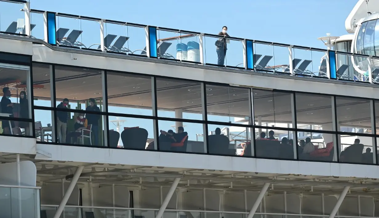 Penumpang dan awak terlihat pada kapal pesiar Spectrum of the Seas di Hong Kong, Rabu (5/1/2022). Spectrum of the Seas diperintahkan kembali ke kota untuk pengujian virus corona COVID-19 setelah sembilan orang ditemukan memiliki kontak dekat dengan varian Omicron baru-baru ini. (PETER PARKS/AFP)