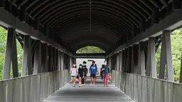 Para pejalan kaki tampak mengenakan masker saat melintasi sebuah jembatan penyeberangan orang di sepanjang Bukit Timah Road di Singapura pada 18 November 2020. (Xinhua/Then Chih Wey)