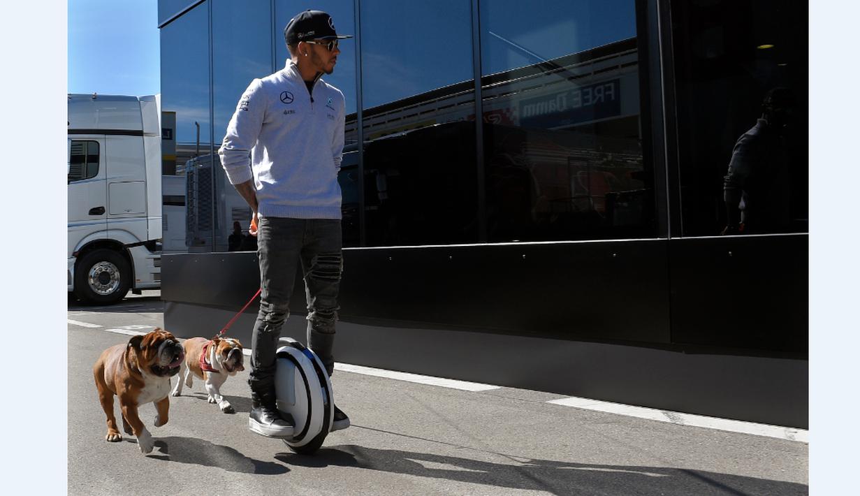 Pebalap Mercedes, Lewis Hamilton, menggunakan legway saat berjalan bersama anjingnya di paddock Sirkuit Catalunya, Barcelona, (2/32016). (AFP/Lluis Gene)