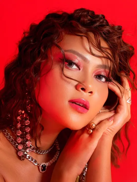 Makeup look seksi nan memesona ala Hanum Mega. Dengan latar foto berwarna merah, makeup dengan nuansa wet look, Hanum Mega terlihat luar biasa dengan rambut merahnya ditata ikal kecil, ditambah berbagai aksesorinya yang sempurna melengkapi. Foto: Instagram.