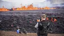 Orang-orang melihat aktivitas di gunung berapi Fagradalsfjall di Islandia pada Rabu (3/8/2022), yang terletak 32 kilometer (20 mil) barat daya ibu kota Reykjavik dan dekat dengan Bandara Internasional Keflavik. Video menunjukkan gunung berapi itu memuntahkan magma dari celah sempit sekitar 100 hingga 200 meter di atas bidang lava dari letusan tahun lalu. (AP Photo/Marco Di Marco)