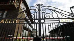 Seorang penjaga keamanan berada di dalam gerbang utama ke Wimbledon utama menuju Wimbledon di London, Rabu (1/4/2020). Turnamen grand slam Wimbledon yang dijadwalkan digelar 19 Juni-21 Juli tahun ini terpaksa dibatalkan karena pandemi virus corona. (AP/Kirsty Wigglesworth)