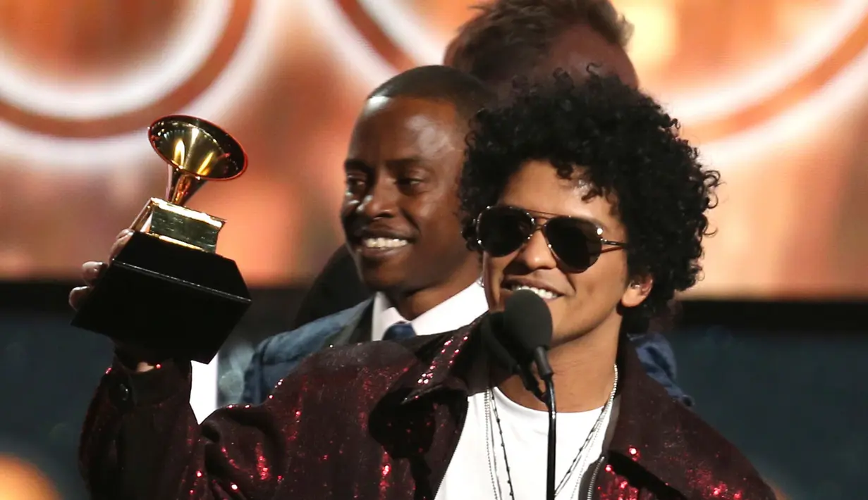 Penyanyi R&B, Bruno Mars mengangkat trofi Song of The Year pada ajang Grammy Awards 2018 di New York City, Minggu (28/1). Tak kurang dari 6 piala Grammy berhasil dibawa pulang termasuk song of the year untuk That’s What I Like. (Matt Sayles/Invision/AP)