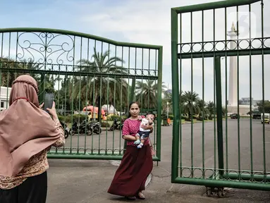 Warga berfoto di depan gerbang masuk Monumen Nasional (Monas), Jakarta, Minggu (15/11/2020). Meski masih ditutup untuk umum sejak awal pandemi Covid-19, kawasan Monas tetap ramai dikunjungi warga untuk sekadar mengisi akhir pekan. (merdeka.com/Iqbal S Nugroho)