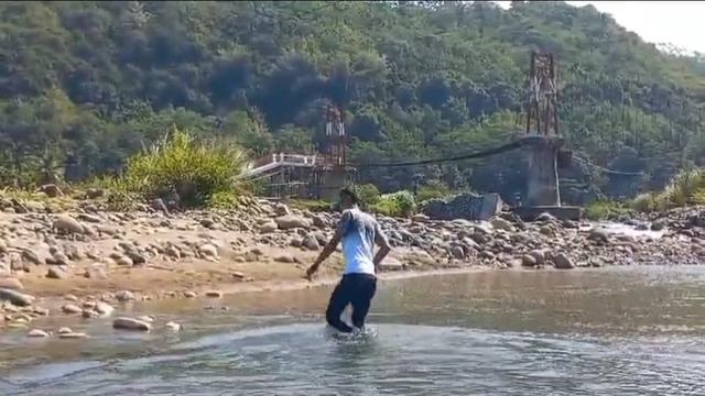 Salah satu warga terpaksa menyebrangi sungai Cirompang, Desa Jagabaya Kecamatan Mekarmukti, Garut, karena akses satu-satunya jembatan rawayan yang terputus belum diperbaiki. (Liputan6.com/Jayadi Supriadin)