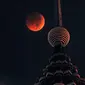 Bulan berwarna merah darah terlihat di atas Menara Petronas saat terjadinya fenomena gerhana bulan total  di Kuala Lumpur, Malaysia, Sabtu (28/7). Gerhana bulan terlama pada abad ini dapat disaksikan di seluruh dunia dengan mata telanjang. (AP/Yam G-Jun)