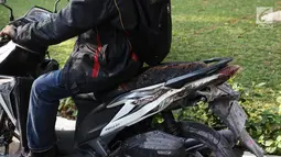 Pengendara membawa sepeda motor Vario yang terkena ledakan salah motor Yamaha Mio Soul GT di parkiran Kemlu, Jakarta, Rabu (7/8/2019). Ledakan motor yang diduga akibat korsleting listrik berdampak beberapa motor ikut terbakar. (Liputan6.com/Angga Yuniar)