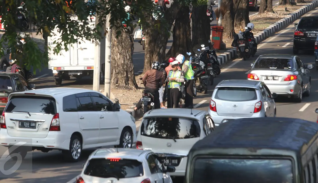 Petugas kepolisian menilang pesepeda motor yang melanggar lalu lintas di kawasan Kemayoran, Jakarta, Kamis (18/8). (Liputan6.com/Immanuel Antonius)