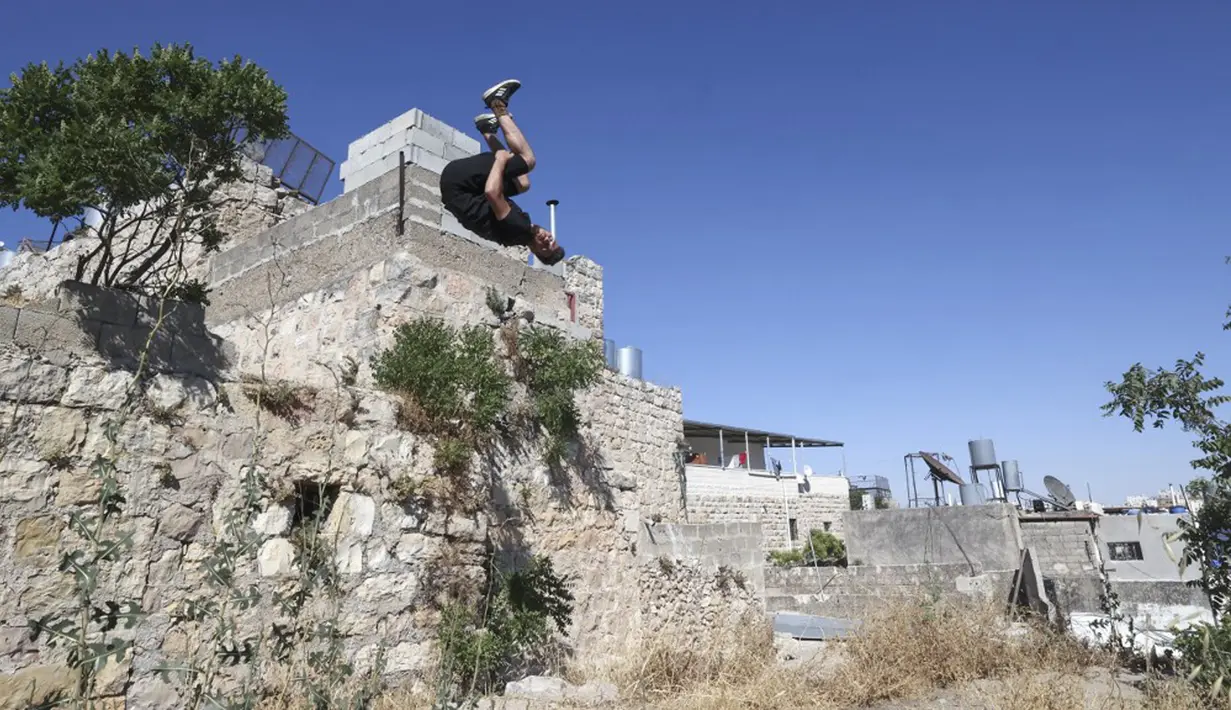 Pemuda Palestina Abdallah al-Natsheh berlatih parkour di atas atap dan tangga rumah batu tradisional di Kota Hebron, Tepi Barat, Sabtu (5/6/2021). (HAZEM BADER/AFP)